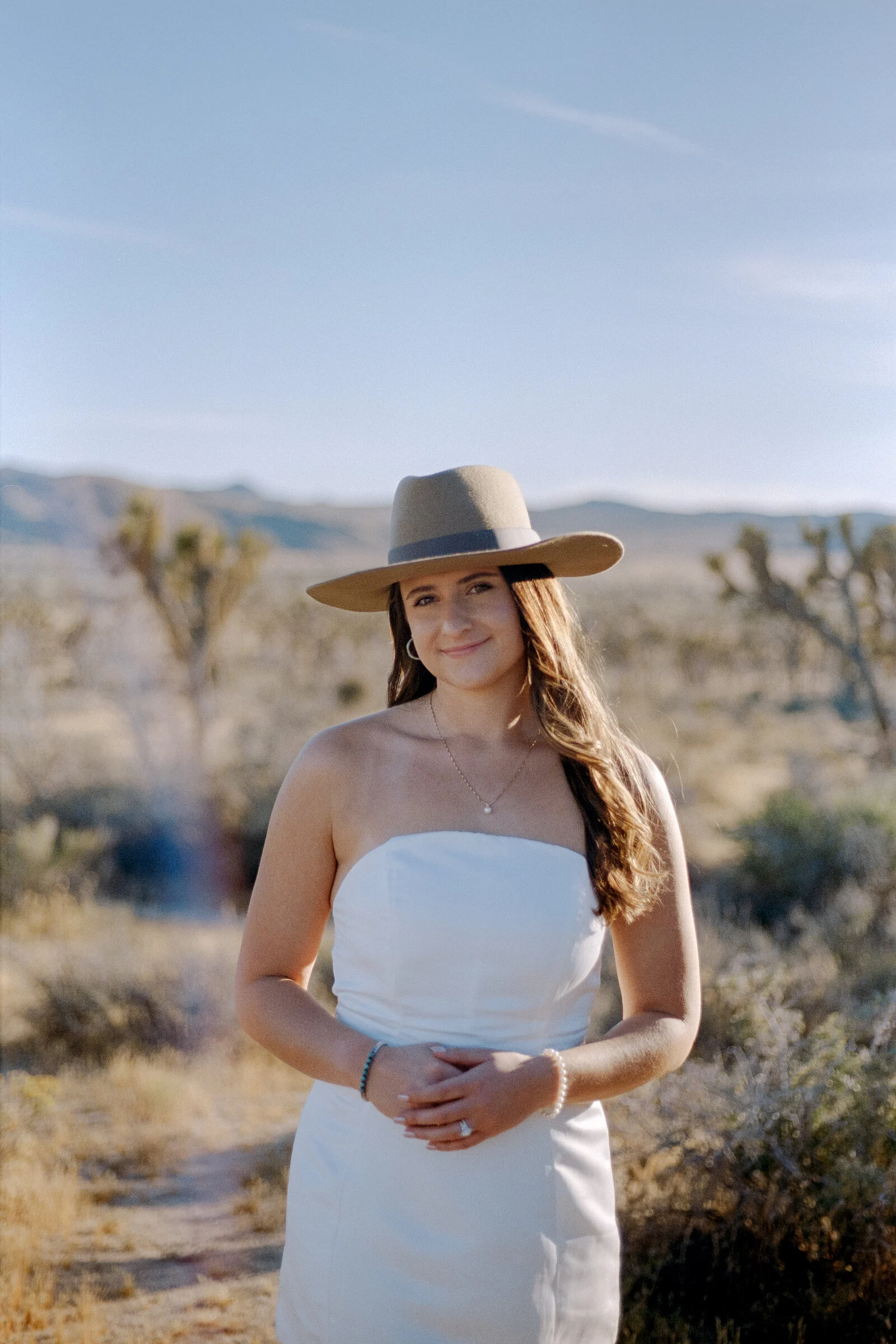 A bride wearing a wide-brimmed hat in the desert, photographed on film