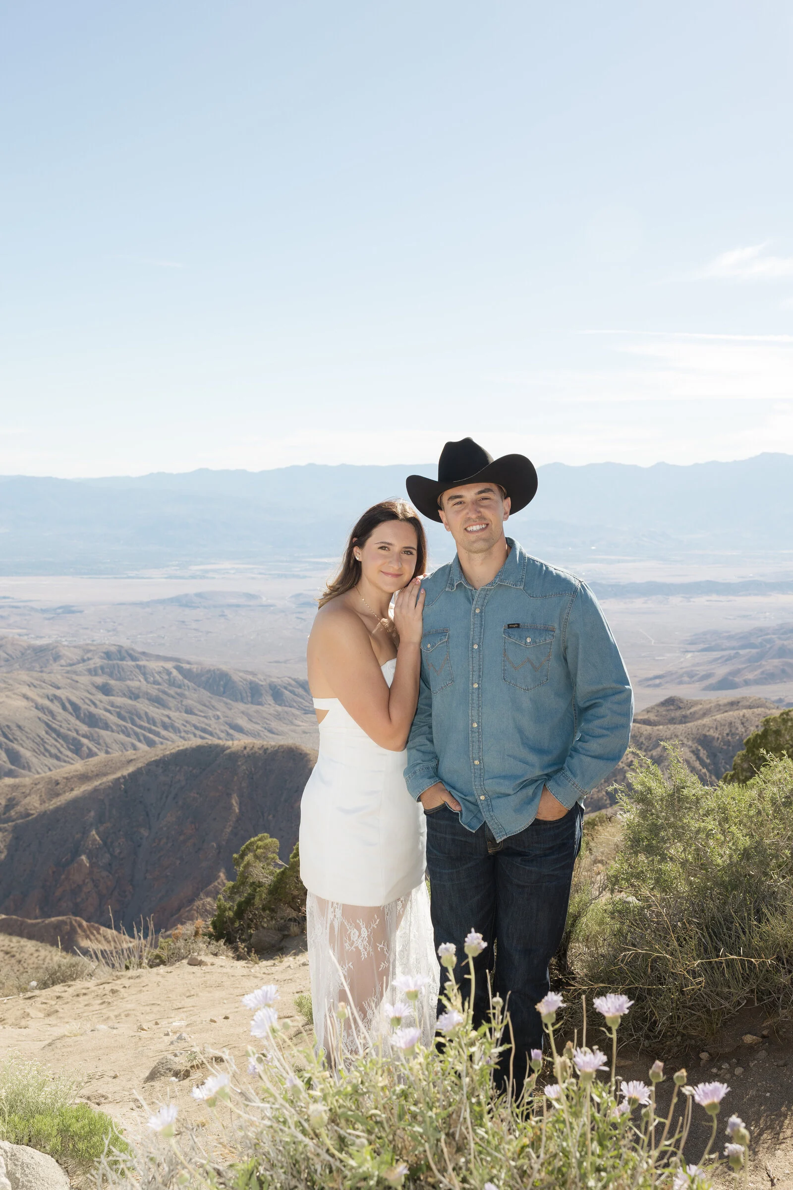A couple embracing above a sweeping mountain landscape