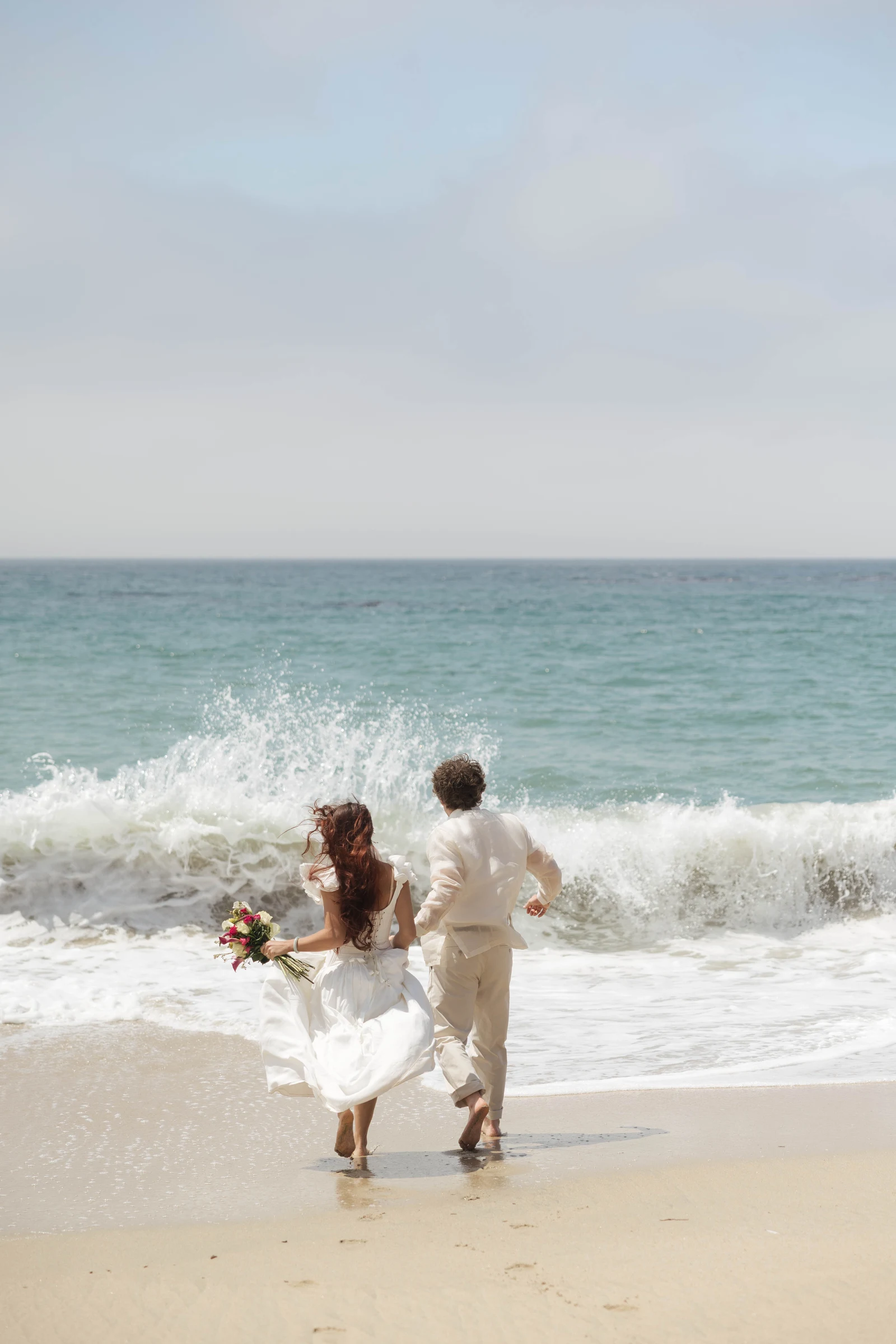 Couple running towards ocean during their elopement in LA