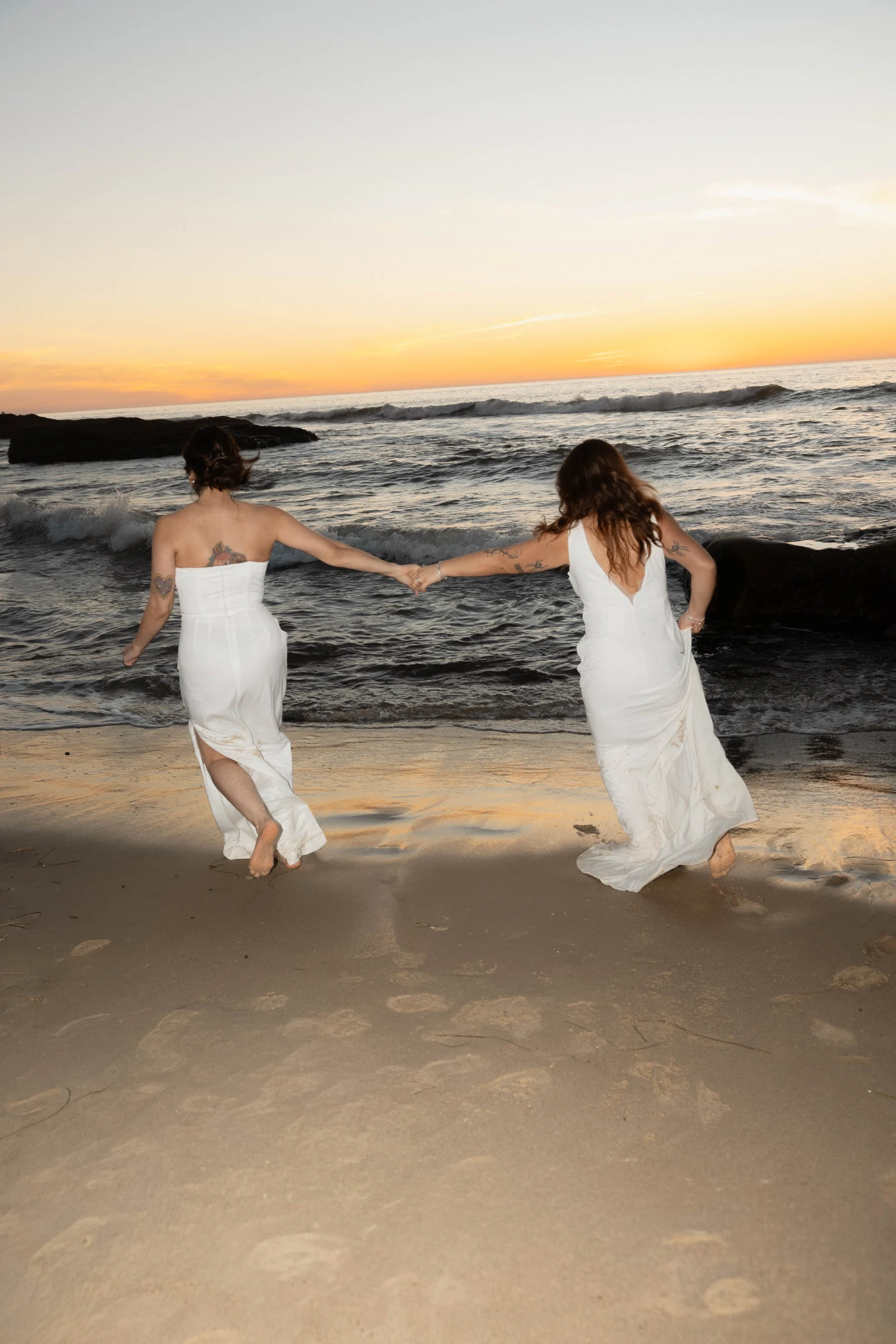 Brides running on the beach in San Diego during sunset