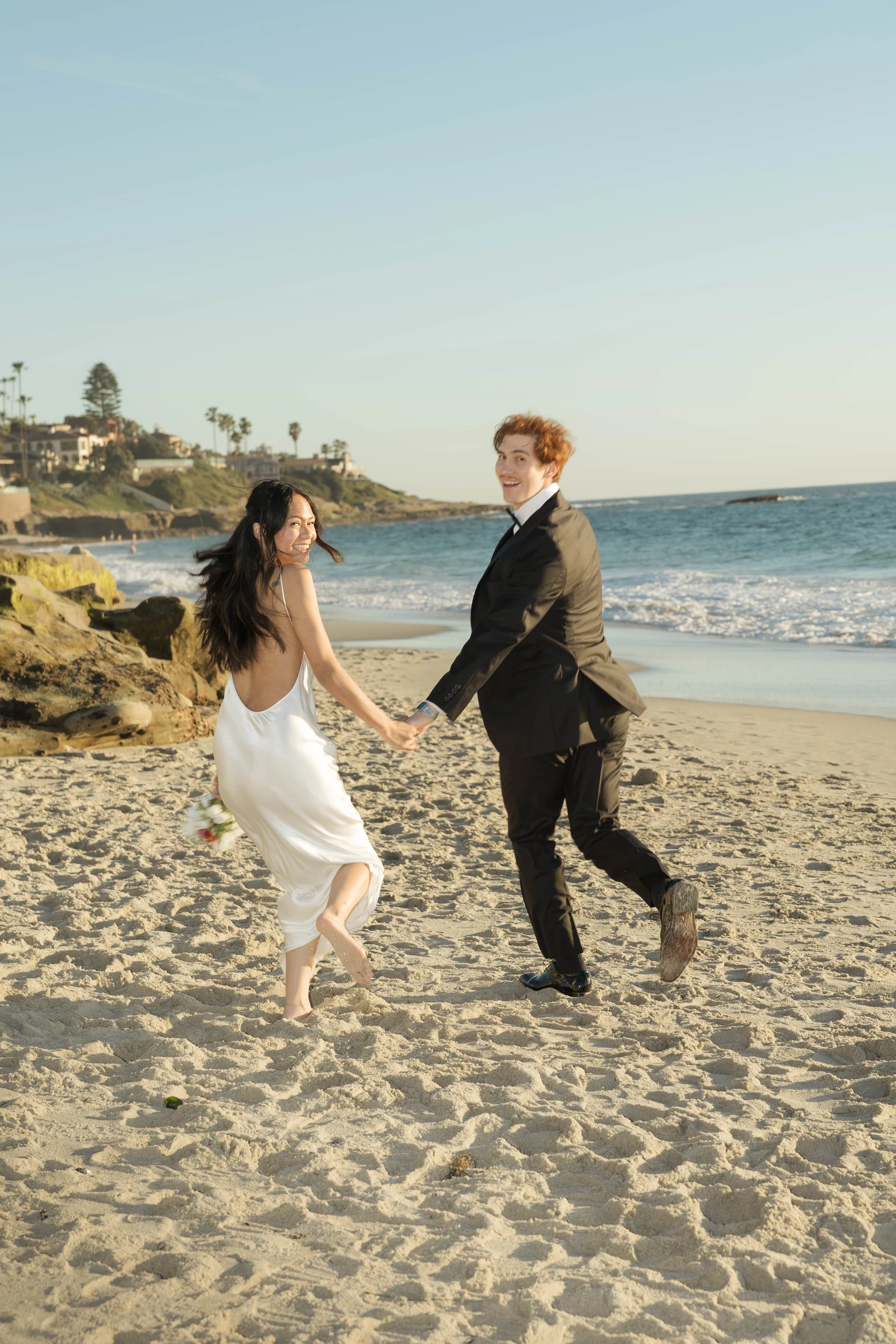 Couple running on the beach during San Diego elopement